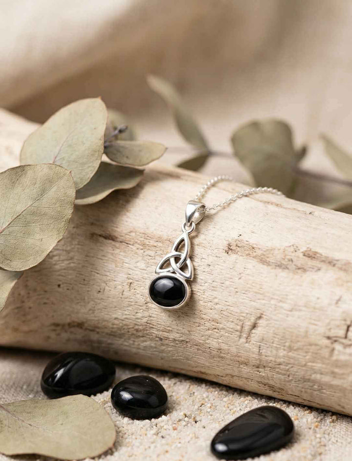 Keltischer Knoten Anhänger aus 925 Silber mit schwarzem Onyx an Silberkette auf Naturmaterialien