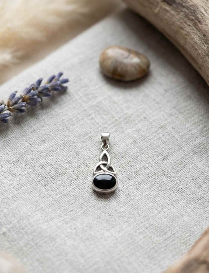 Silberanhänger mit keltischem Knoten und schwarzem Onyx in ruhiger Naturkulisse