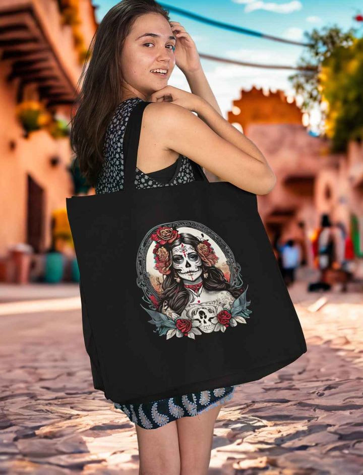 Junge Frau mit schwarzem La Catrina Organic Shopping Bag, stehend auf einer typischen mexikanischen Straße während des Dia de los Muertos – Runental.de