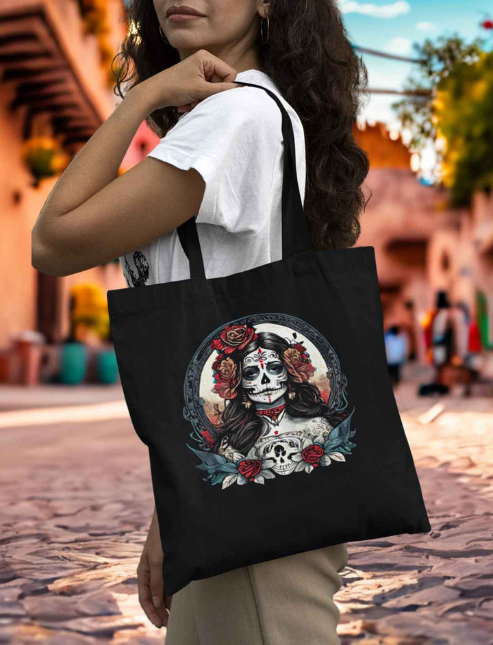 Junge Frau mit schwarzem La Catrina Organic Tote Bag, stehend auf einer typischen mexikanischen Straße während des Dia de los Muertos – Runental.de