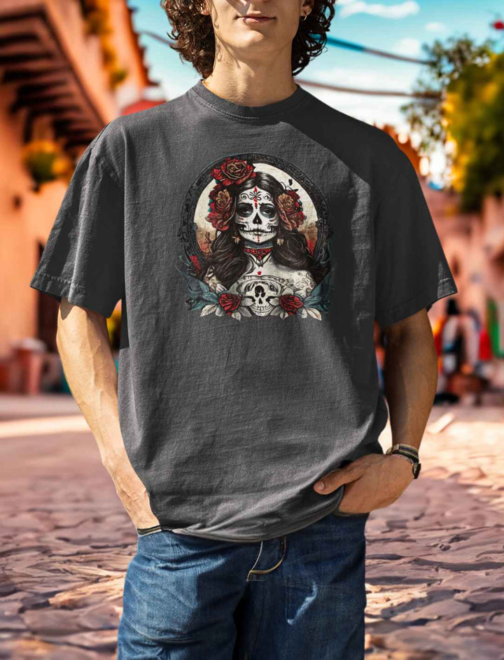 Junger Mann zeigt den La Catrina Organic Oversized T-Shirt in modernem India Ink Grey, stehend in einer charakteristischen mexikanischen Gasse während des Día de los Muertos – Runental.de