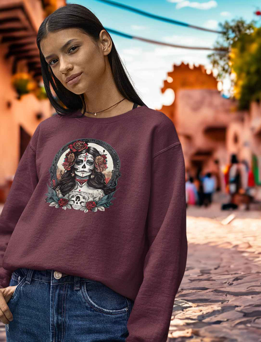 Junge Frau im Burgund La Catrina Organic Sweatshirt, stehend auf einer malerischen mexikanischen Straße während des Dia de los Muertos – Runental.de
