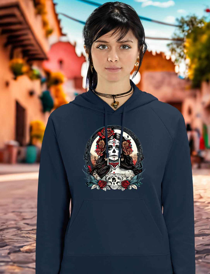 Junge Frau trägt La Catrina Organic Damen Hoodie in French Navy, stehend auf einer malerischen mexikanischen Straße zum Anlass des Dia de los Muertos – Runental.de.