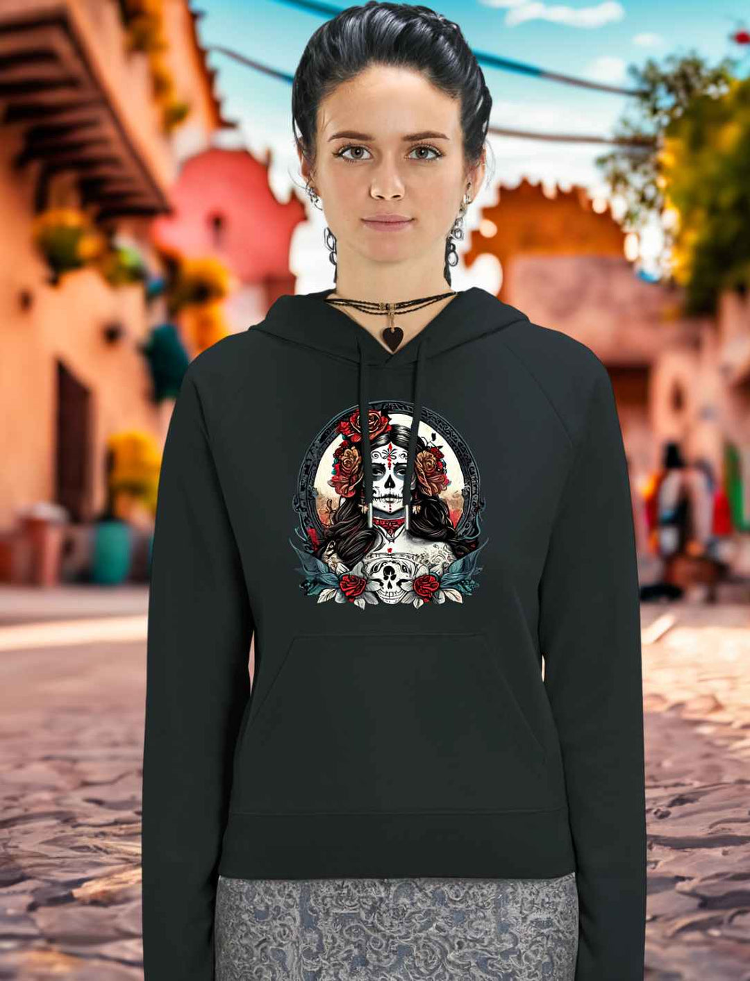 Junge Frau trägt La Catrina Organic Damen Hoodie in Schwarz, stehend auf einer typischen mexikanischen Straße während des Dia de los Muertos – Runental.de.