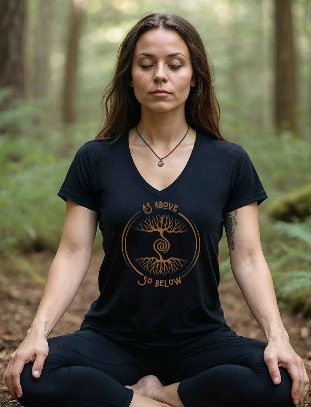 Frau trägt das Damen V-Neck Shirt „Lebenswurzel der Verbundenheit“ in Schwarz mit Weltenbaum-Design im Wald