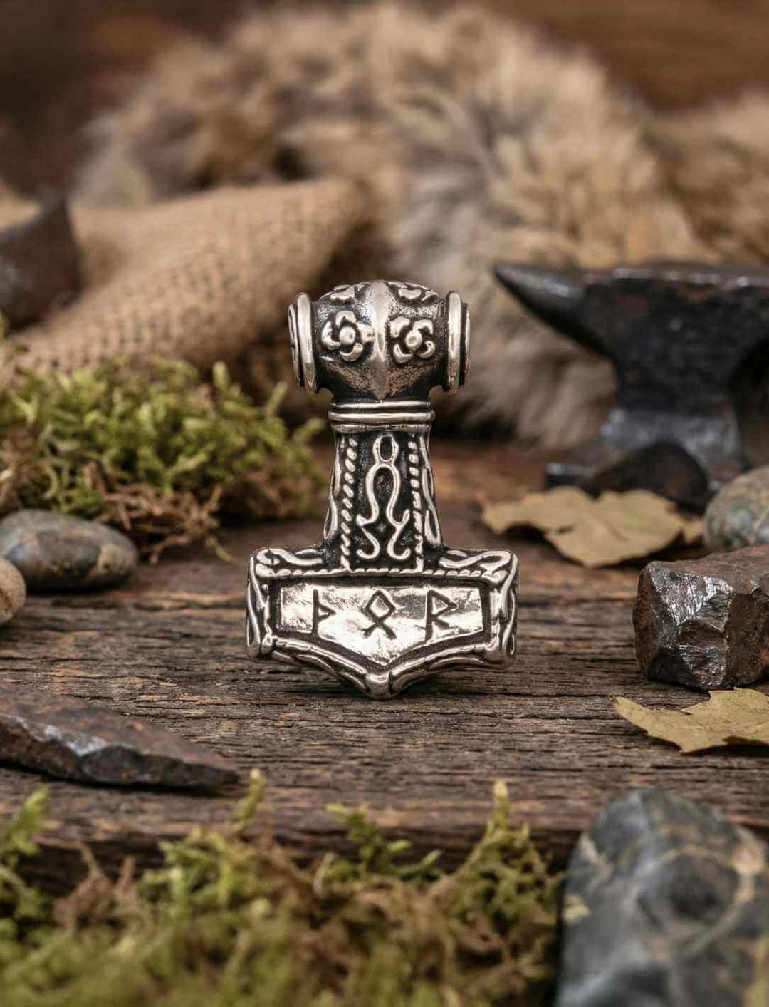 Thors Hammer Silberanhänger mit Elder-Futhark-Runen auf rustikalem Holz und Fell