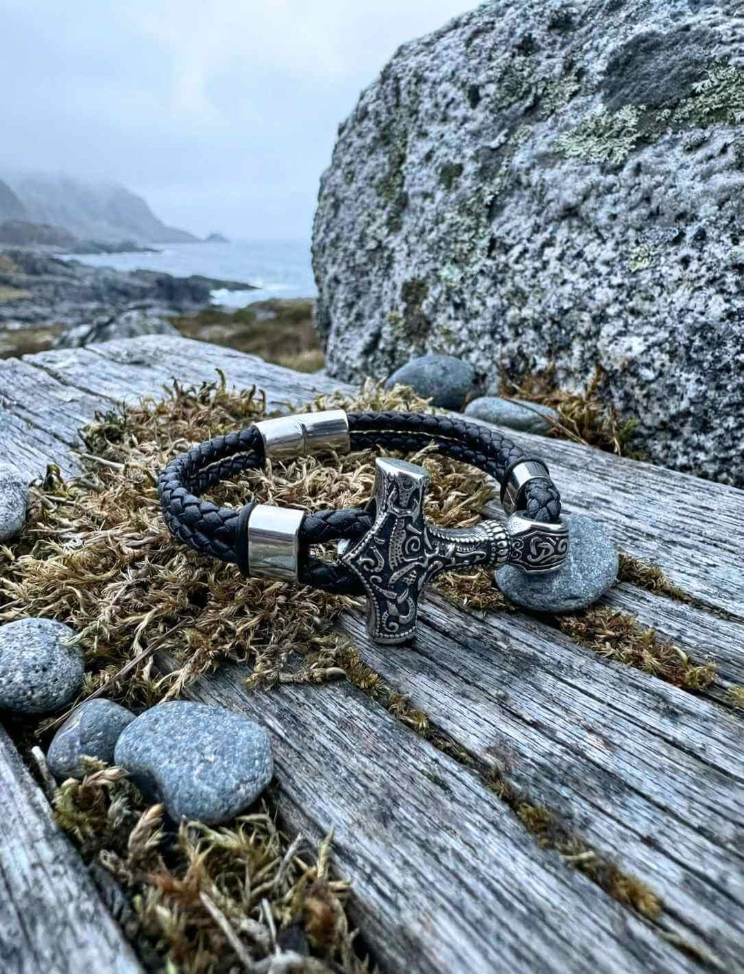 Nordisches Lederarmband mit Thors Hammer auf Felsen in rauer Umgebung