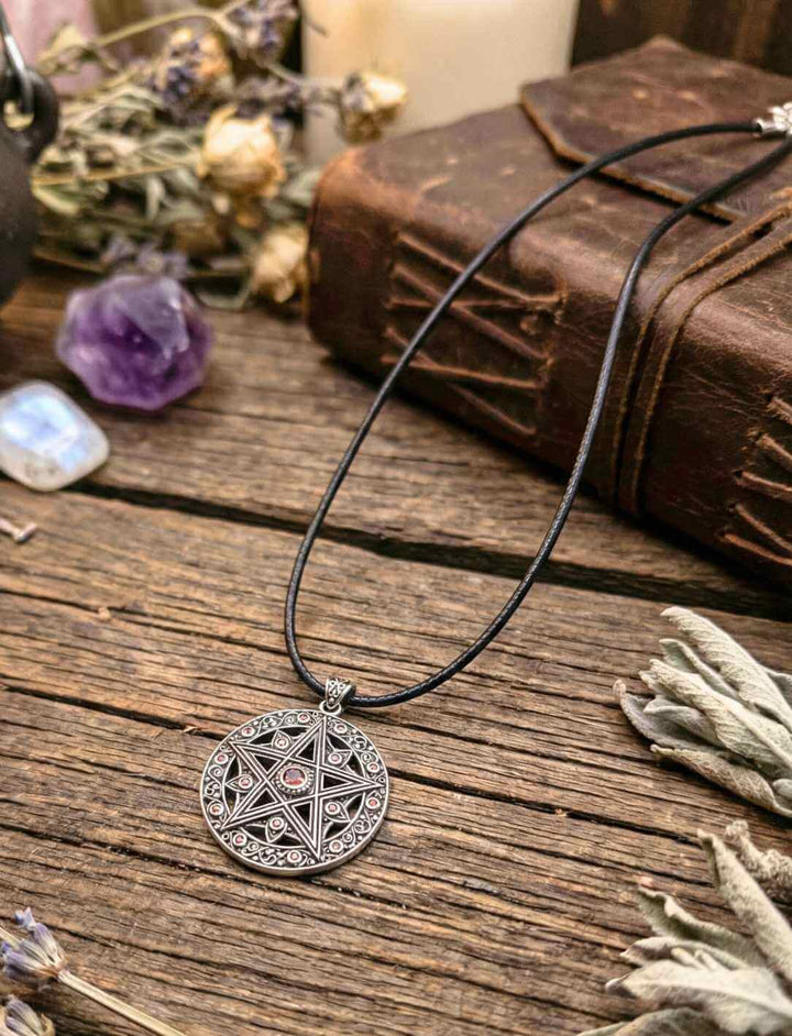 Pentakel Schutzamulett aus Silber mit roten Zirkonia auf rustikalem Holztisch – Wicca Schmuck mit Elementesymbolik