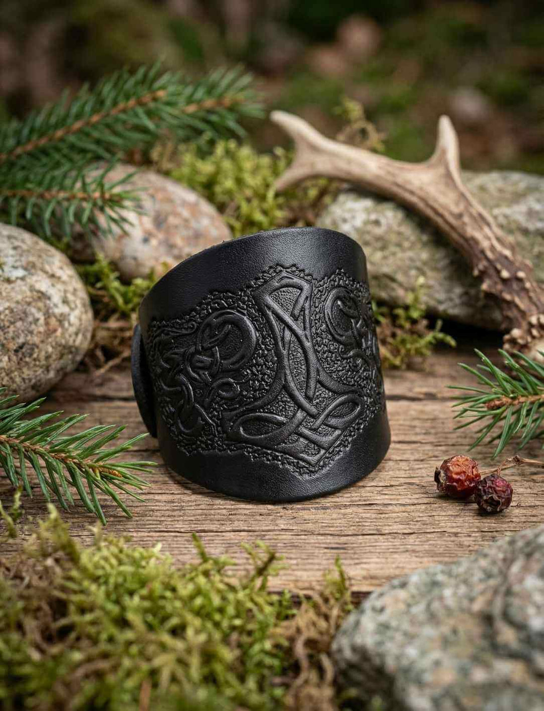 Schwarzes Lederarmband mit Mjölnir Prägung im nordischen Stil, auf Holz und Moos arrangiert