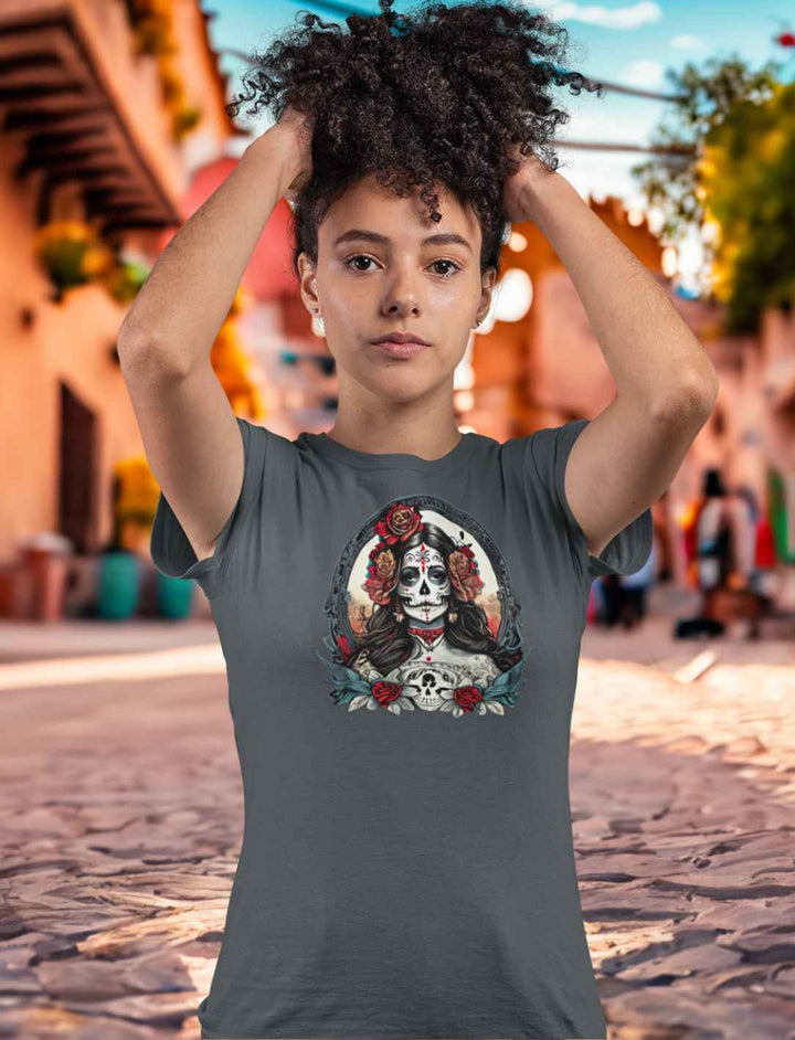 Junge Frau im La Catrina Damen Shirt in tiefem Anthrazit, inmitten einer ruhigen mexikanischen Gasse, dekoriert für die Feierlichkeiten des Día de los Muertos – Runental.de.