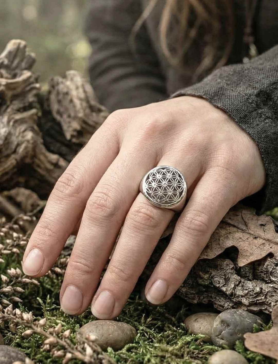 Blume des Lebens Silberring am Finger getragen, feines geometrisches Symbol im natürlichen Umfeld