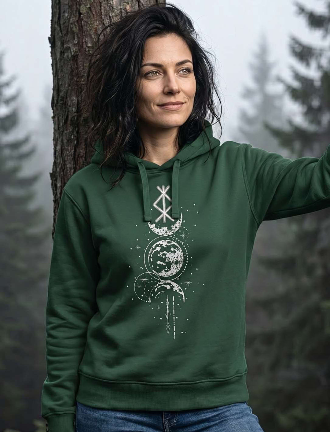 Frau lehnt an Baum und trägt Runen Hoodie in Dunkelgrün mit Mondphasen-Design