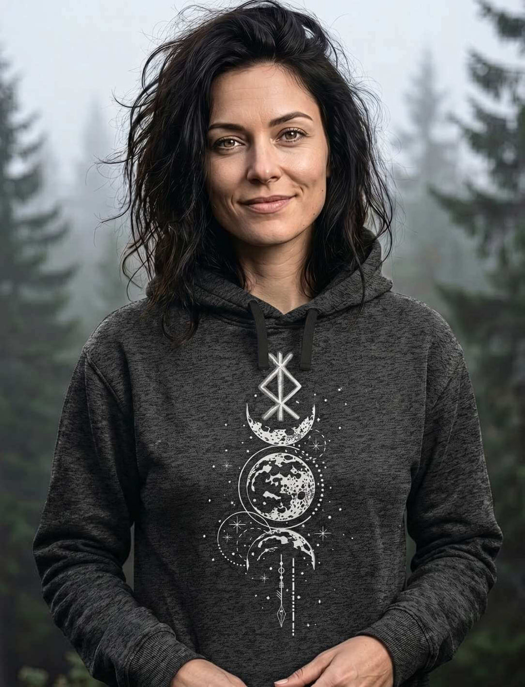 Frau trägt Runen Hoodie in Dark Heather grey meliert mit Mondphasen-Design vor nebligem Wald