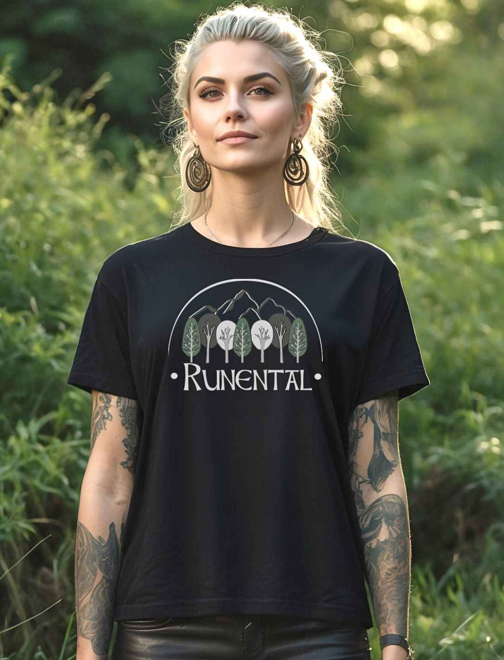 Blonde Frau trägt das schwarze  “Runental Fan-Kollektion” Damen Organic T-Shirt im Wald – Mystisches Design mit Runental-Logo, eingefangen in einer natürlichen Umgebung.