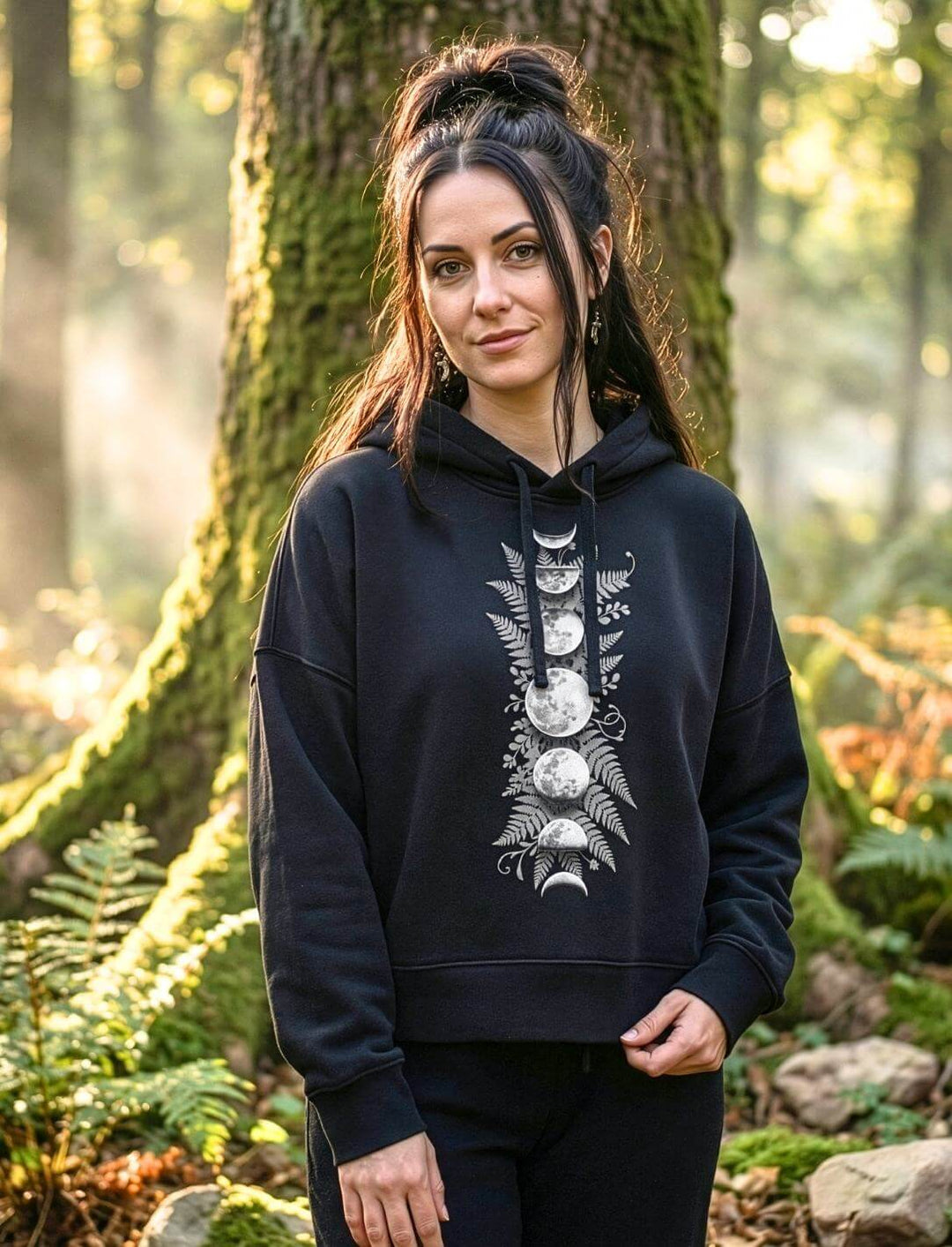 Frau trägt schwarzen Sacred Moon Boxcut Hoodie im Wald – Mondphasen Bio Hoodie Runental