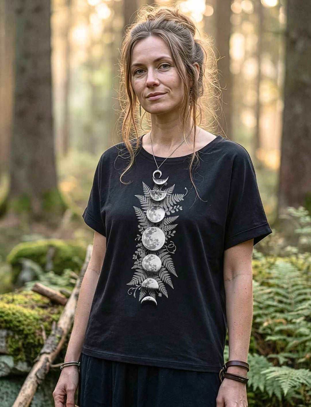 Sacred Moon – Forest Mysteries Damen Relaxed Shirt Schwarz mit Mondphasen und Farnmotiv, getragen von Frau im Wald