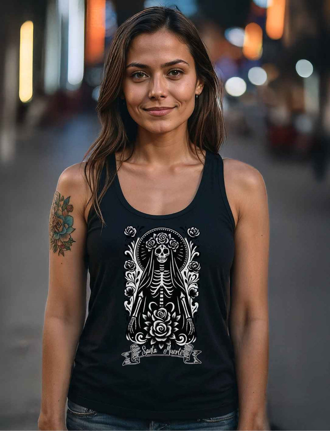 Frau in dunkler Straße trägt schwarzes Santa Muerte Tank Top mit weißem Design aus der La Catrina Collection.