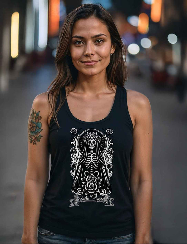 Frau in dunkler Straße trägt schwarzes Santa Muerte Tank Top mit weißem Design aus der La Catrina Collection.