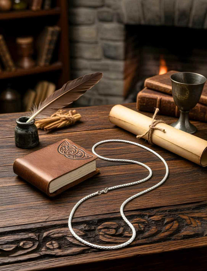 Edelstahlkette im mittelalterlichen Ambiente mit Buch, Feder und Kaminfeuer – stimmungsvolles Runental Produktbild
