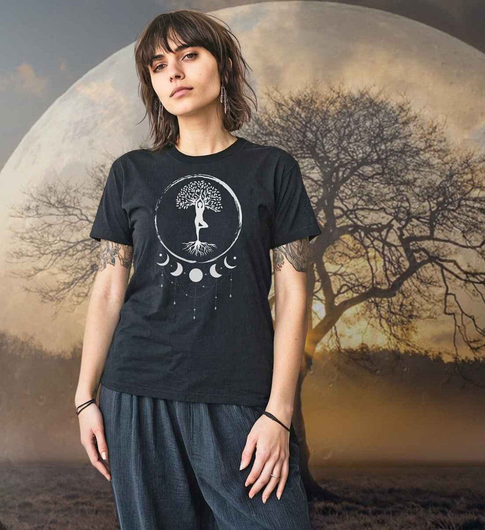 Junge Frau trägt das schwarze Damen T-Shirt Seelenbaum-der-Mondträumer. Im Hintergrund ist ein mystischer Mond und ein Lebensbaum zu sehen.