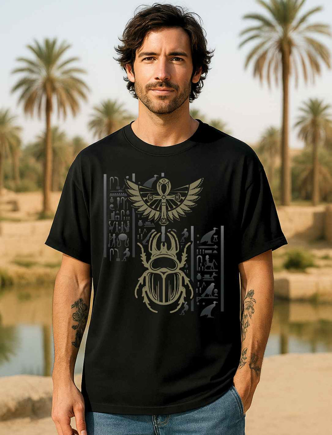 Männliches Model vor Palmenlandschaft trägt schwarzes Oversized Bio-Shirt mit goldfarbenem Skarabäus und ägyptischen Symbolen