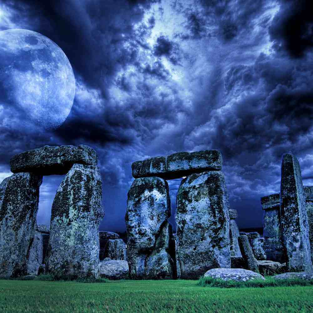 Stonehenge bei Nacht unter einem leuchtenden Vollmond im Hintergrund.