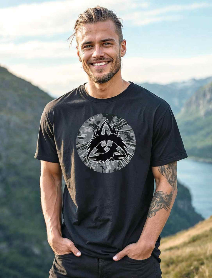 Mann trägt das schwarze Wikinger-T-Shirt The Raven Clan mit Raben-Design in einer nordischen Landschaft.