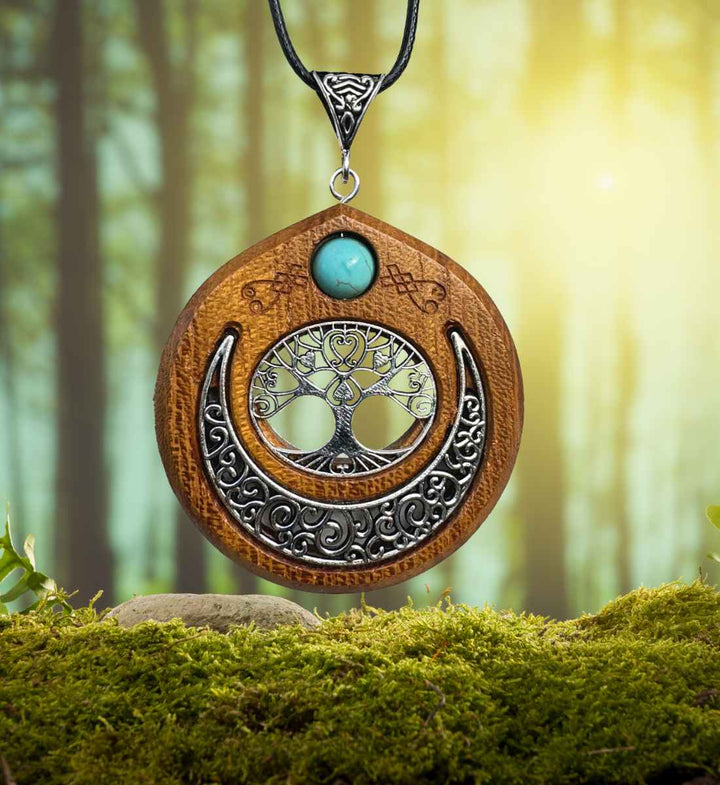 Keltische Lebensbaum Halskette mit türkiser Perle präsentiert vor einem natürlichen Hintergrund aus Wald und Moos