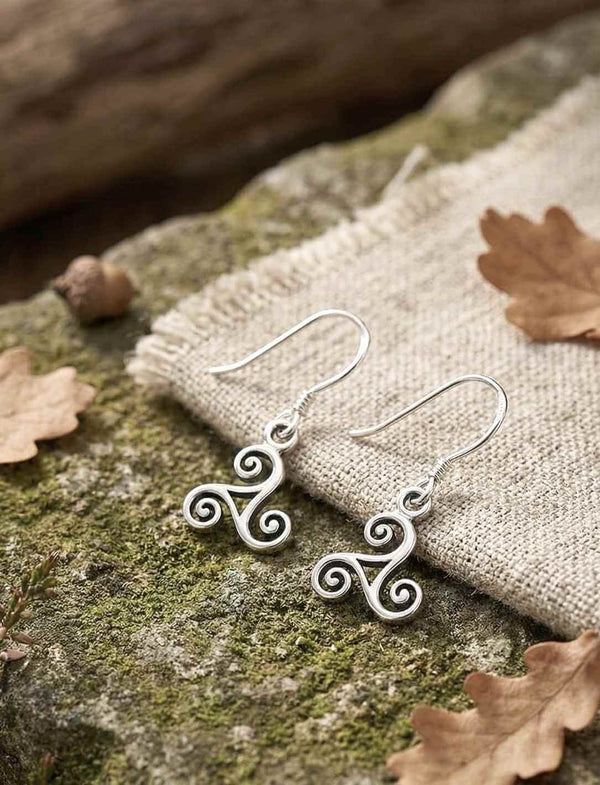 Triskele der stillen Pfade Silber Ohrhänger auf Stein und Leinenstoff in Naturkulisse