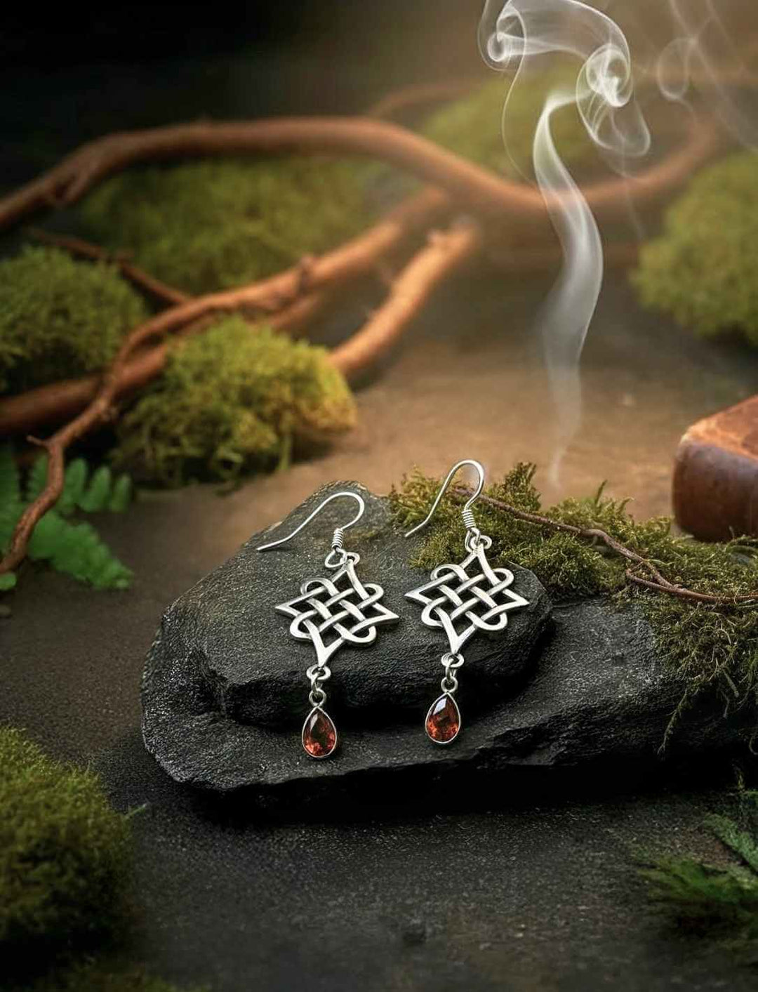 Keltische Knotenohrringe aus 925 Sterling Silber mit rotgoldenem Zirkonia auf Moos und Stein im Wald