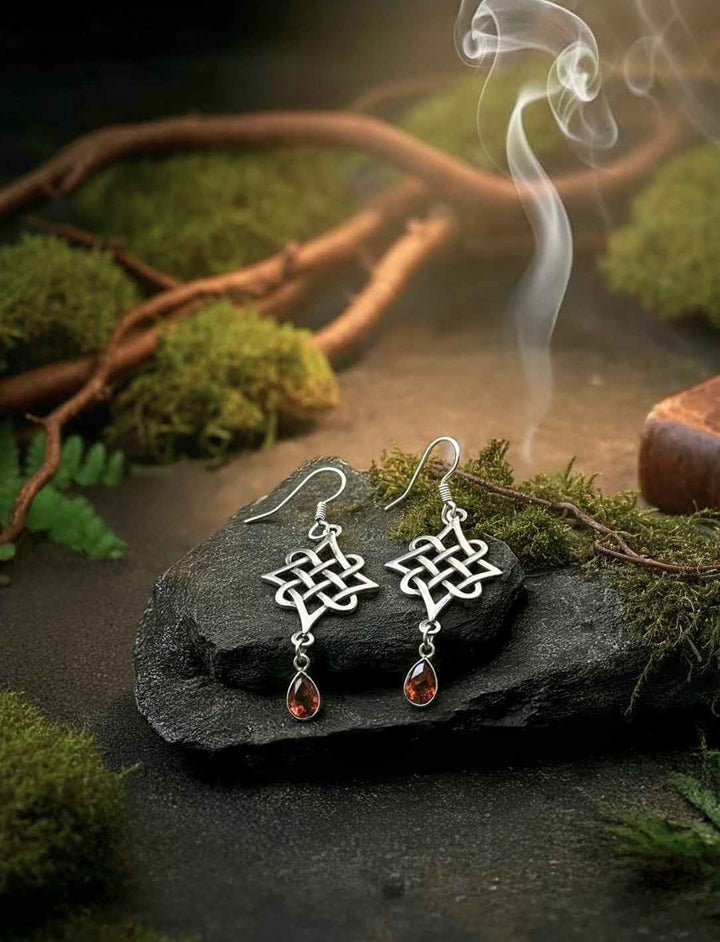 Keltische Knotenohrringe aus 925 Sterling Silber mit rotgoldenem Zirkonia auf Moos und Stein im Wald