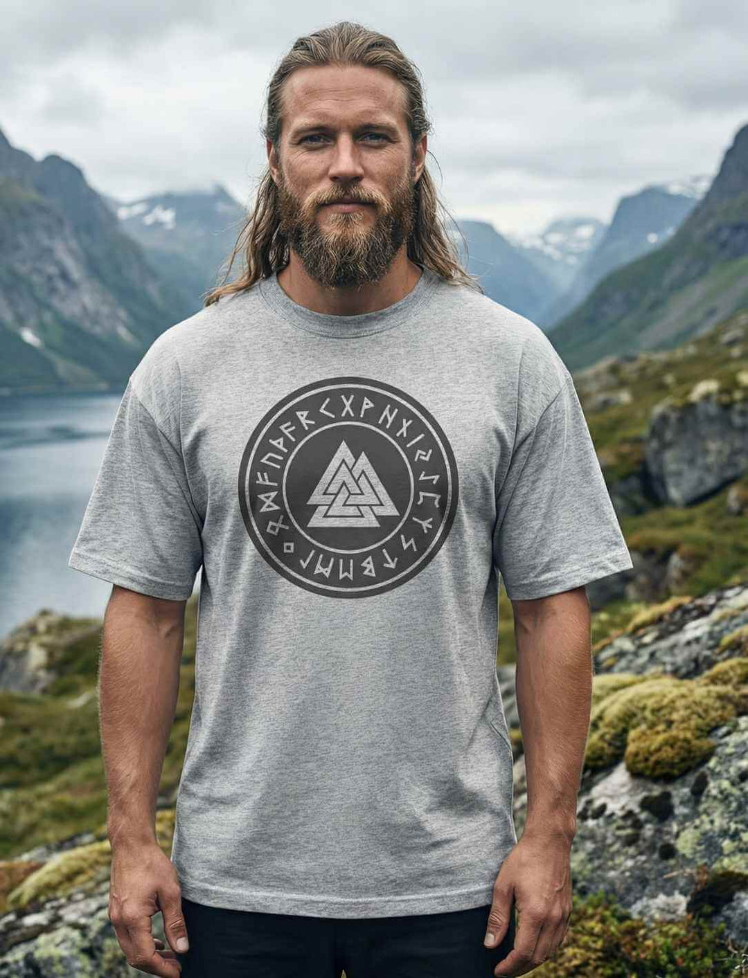 Mann trägt graues Oversized Valknut Shirt mit nordischem Runen Symbol in Naturkulisse