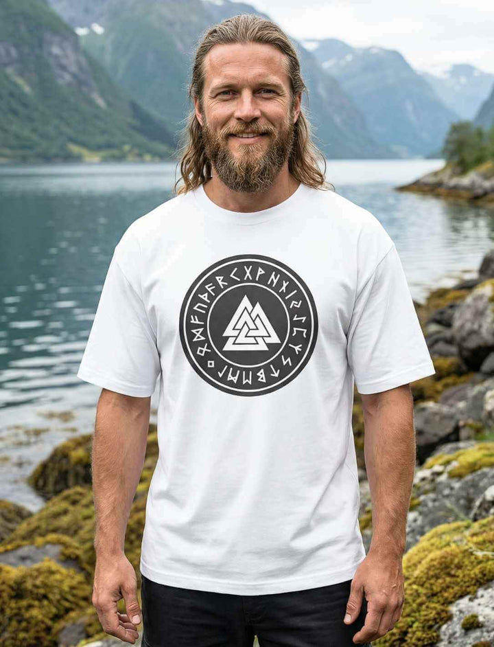 Mann trägt weißes Oversized Valknut Shirt mit nordischem Runen Siegel in nordischer Fjordlandschaft
