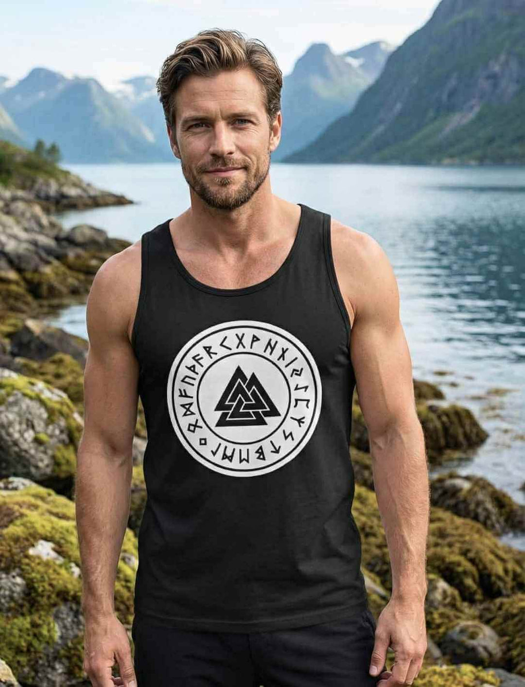 Mann trägt schwarzes Valknut Relaxed Tank Top mit nordischem Runensiegel Motiv am Fjord – Zeichen Odins in Long Fit Passform
