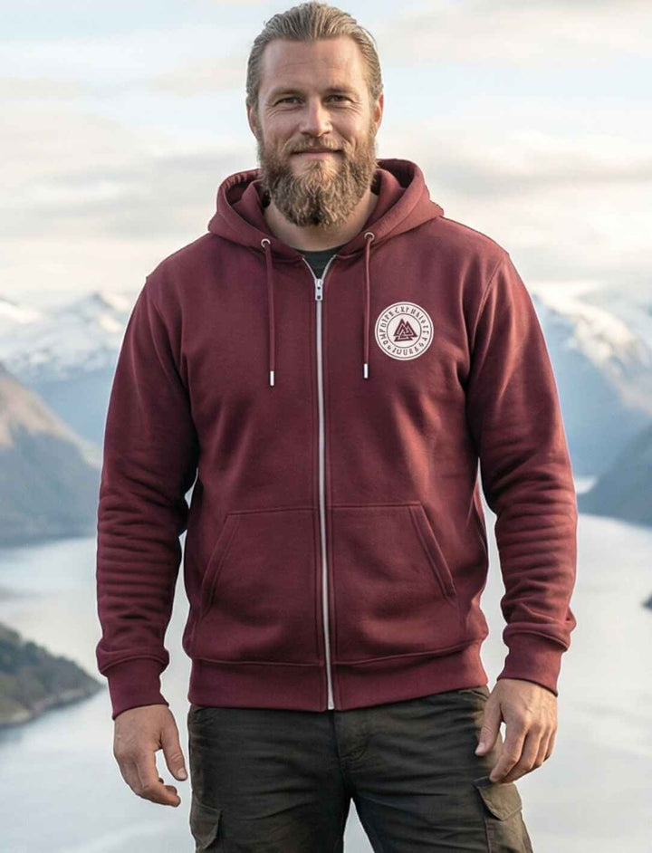 Burgundfarbener Valknut Zip Hoodie, getragen vor Fjordlandschaft, Odins Zeichen als dezentes Brustmotiv.