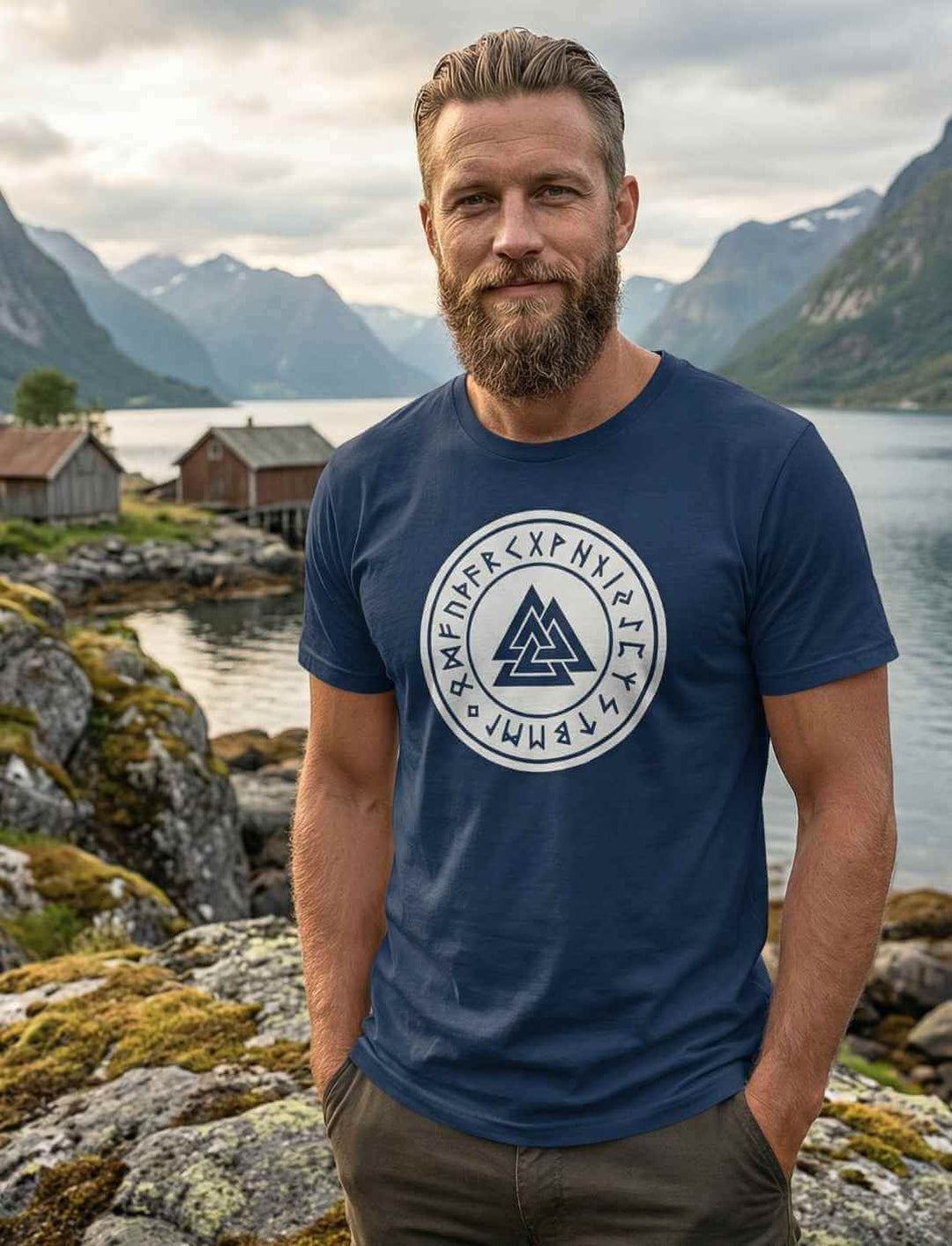 Mann trägt navyfarbenes Valknut Organic Shirt – Zeichen Odins mit nordischem Symbolprint, Wikinger T-Shirt am Fjord