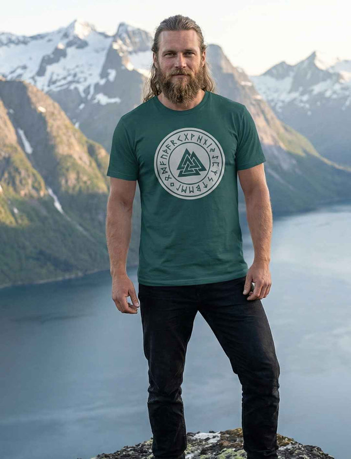 Mann trägt grünes Valknut Organic Shirt – Zeichen Odins mit nordischem Runenkreis, Wikinger Design in Naturkulisse
