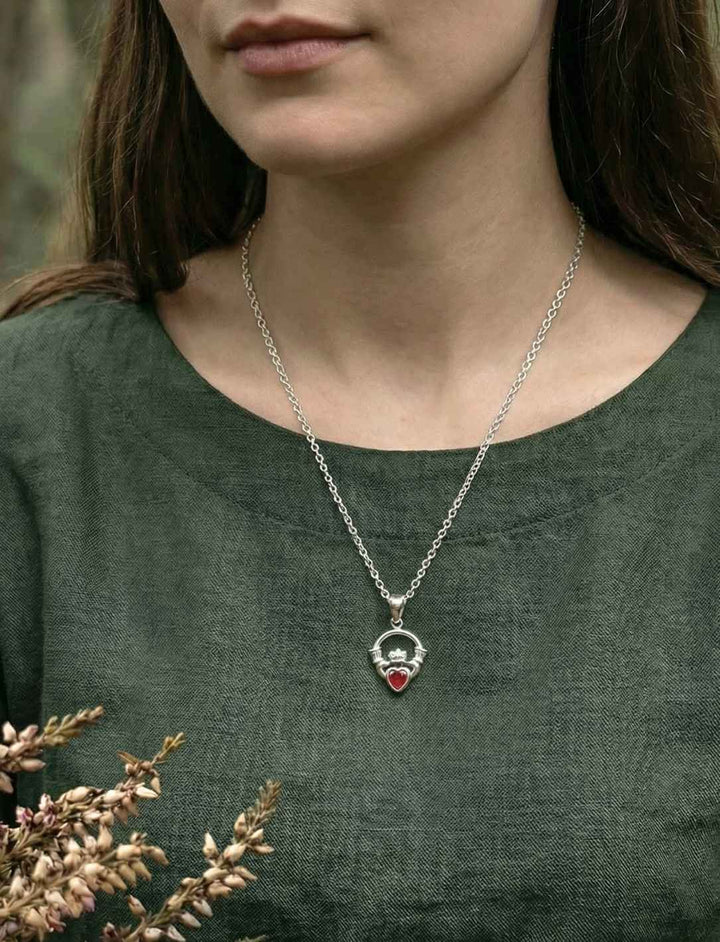 Model trägt Claddagh Medaillon aus 925 Silber mit rotem Herzstein