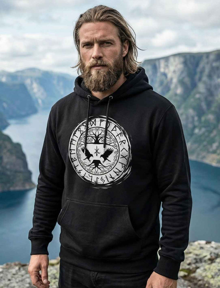 Schwarzer Organic Hoodie mit Yggdrasil-Raben und Runenkreis, getragen in Fjordlandschaft