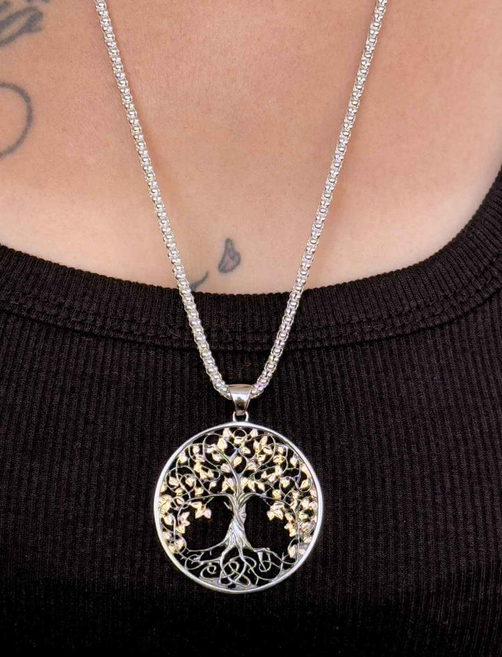 Model trägt Lebensbaum-Medaillon aus Silber, teilvergoldet und schwarz paltiniert, mit Silberkette im Popcorndesign.
