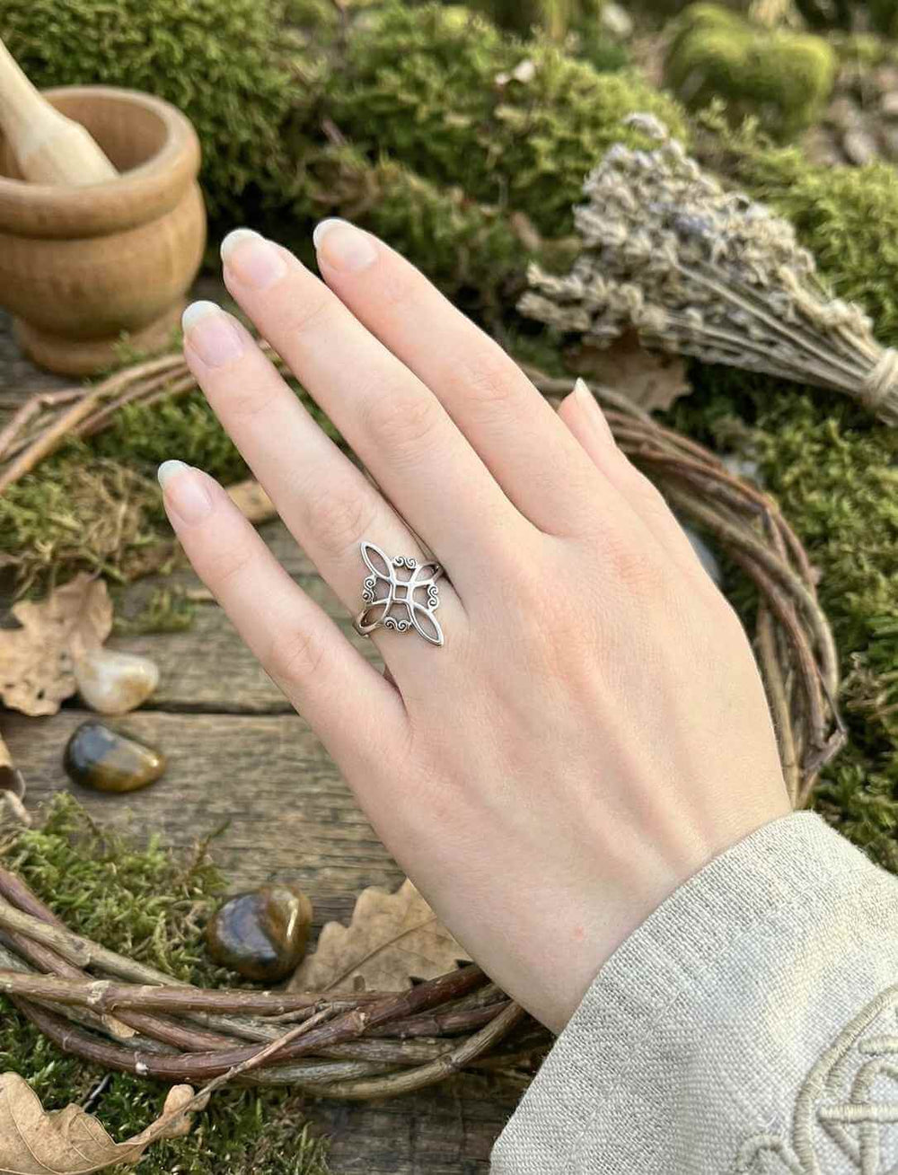 Edelstahlring Witch Knot, getragen am Ringfinger von Frau in natürlicher Umgebung