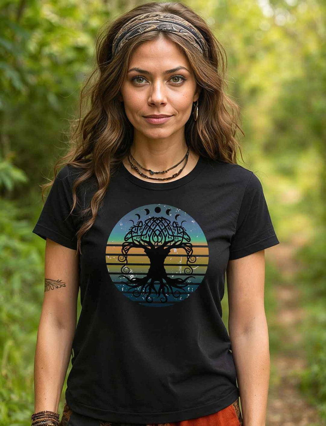 Boho styled Frau mit langen Haaren trägt schwarzes T-Shirt mit Yggdrasil Weltenbaum der Harmonie Motiv im Wald.
