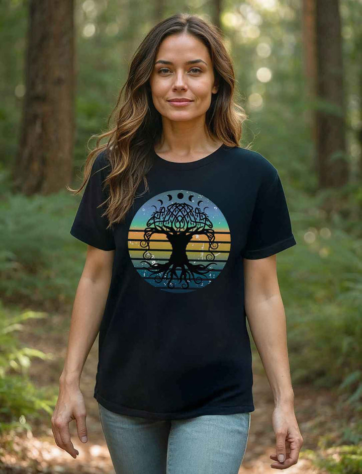 Frau im schwarzen Oversized-Shirt mit Yggdrasil-Motiv, steht im lichten Wald – Symbol für Harmonie, Naturverbundenheit und Stärke.