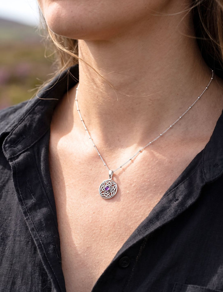 Silberanhänger mit Amethyst an Perlenkette getragen zu offenem schwarzem Leinenhemd