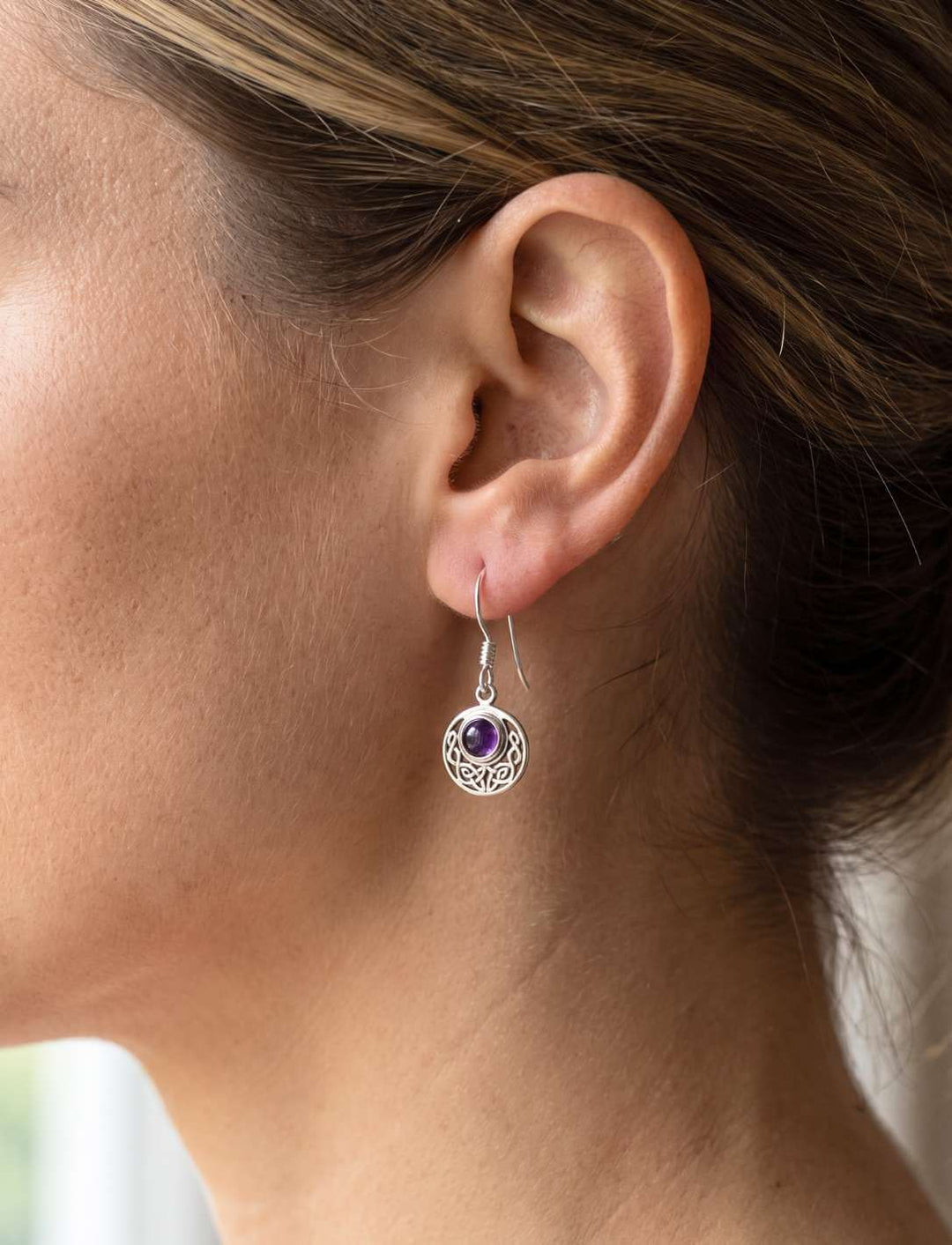 Keltischer Knoten Ohrhänger mit violettem Stein am Ohrläppchen getragen