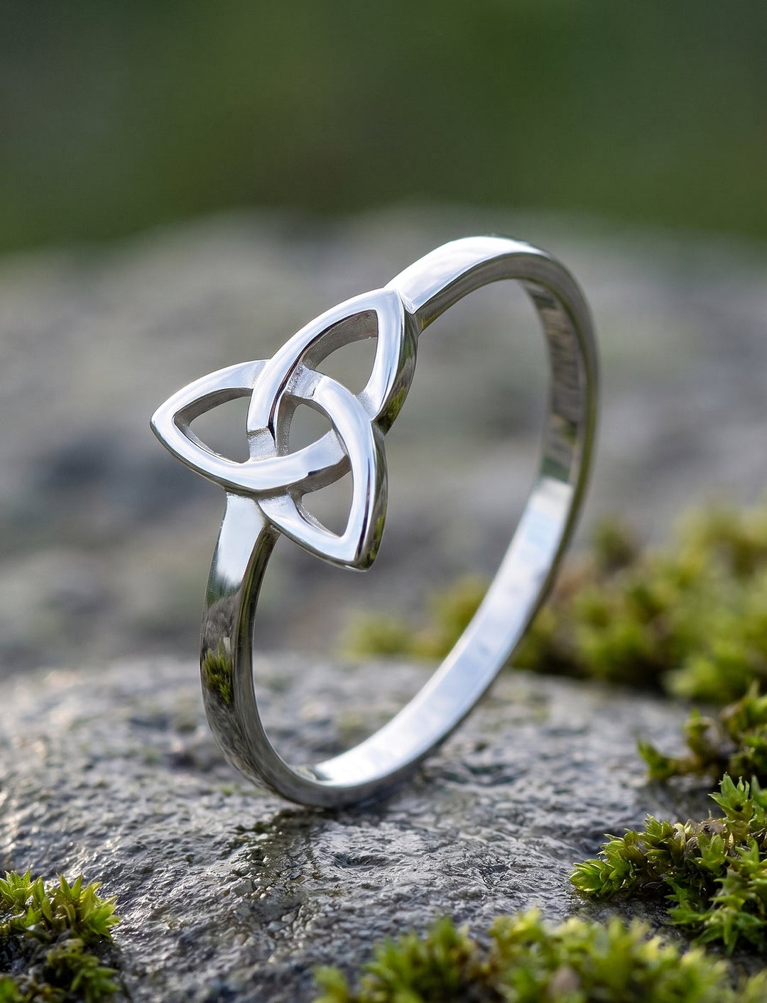 Band der drei Schwestern: Triquetra Ring aus 925 Sterling Silber steht auf moosigem Fels, Nahaufnahme