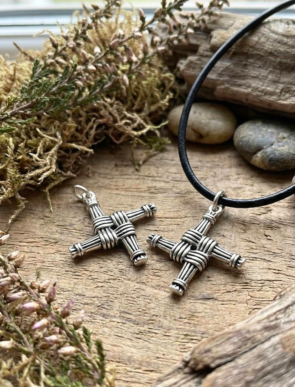 Zwei Brigid Kreuz Anhänger versilbert auf Holz mit Heidekraut und Steinen irisches Schutzzeichen