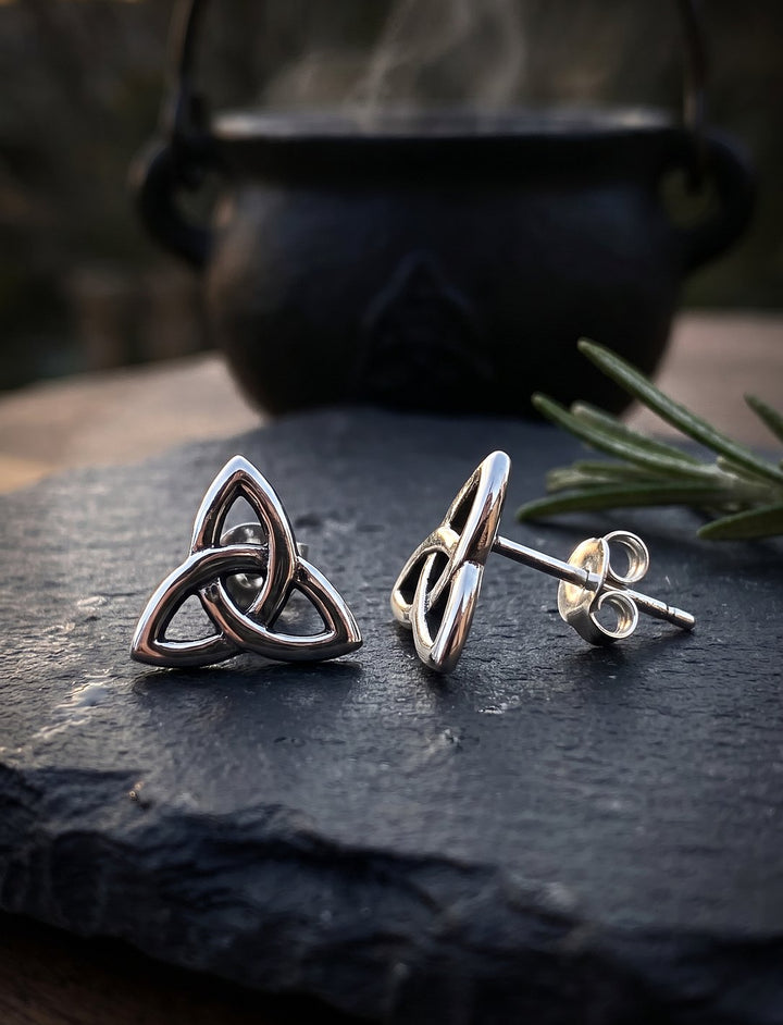 Ceridwens Tropfen – Triquetra Ohrstecker aus 925 Silber auf Schiefer vor einem dampfenden Eisenkessel