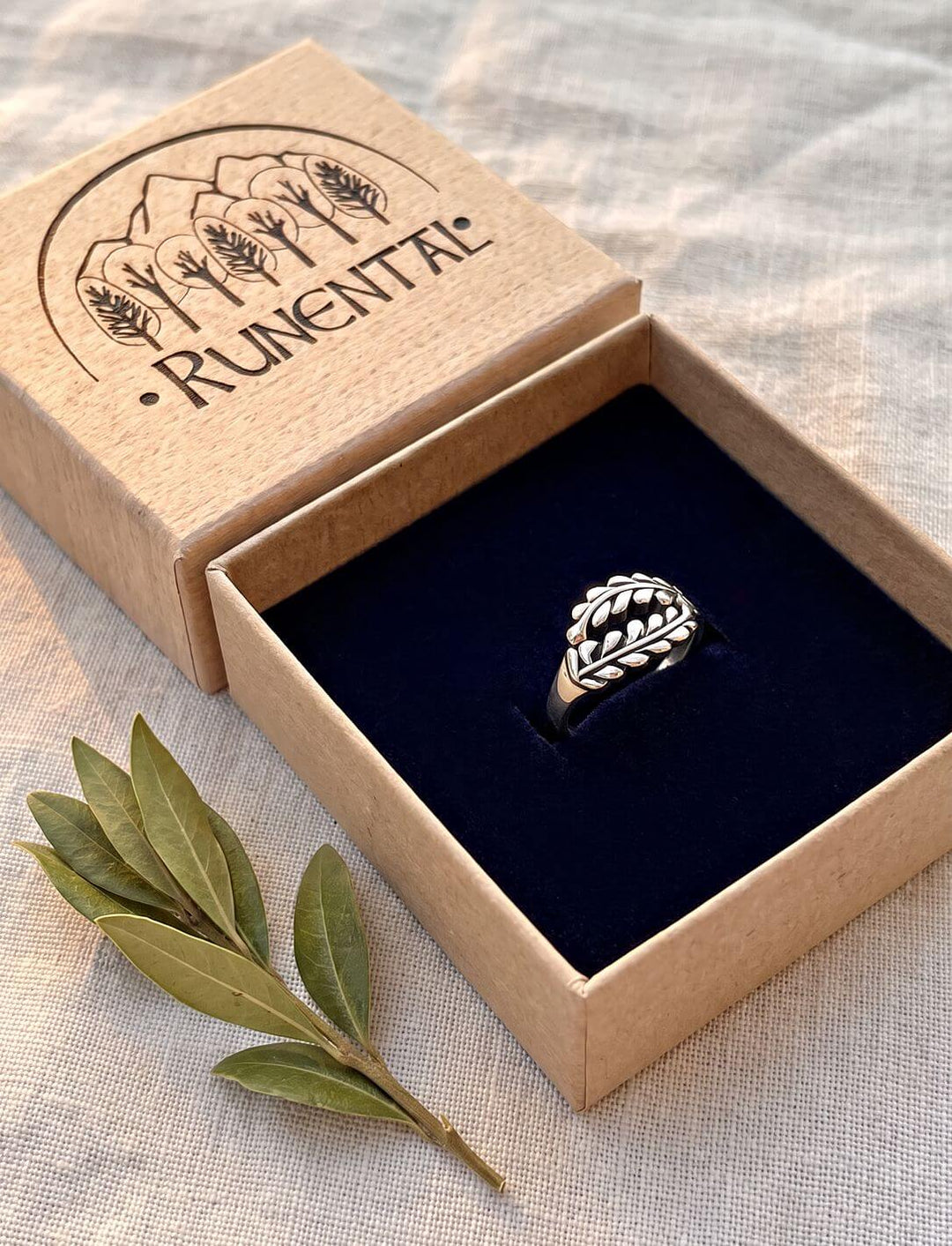 Lorbeerkranz-Ring aus Sterling Silber in der Runental-Geschenkbox mit einem Lorbeerzweig auf Leinen