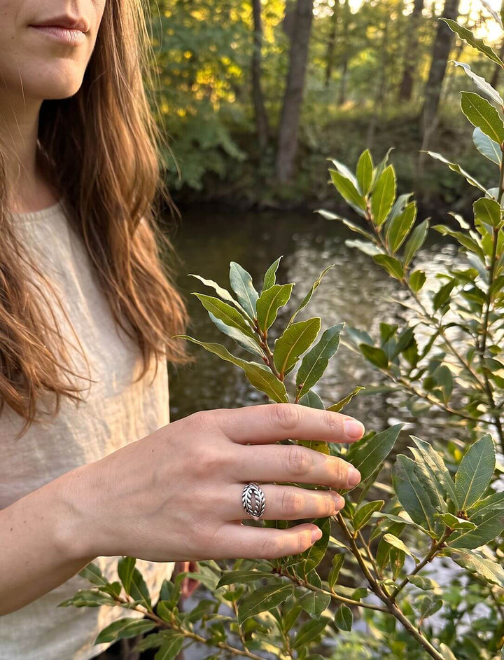 Frau im hellen Leinenshirt trägt den Lorbeer Ring aus Silber an einem Lorbeerstrauch am Fluss